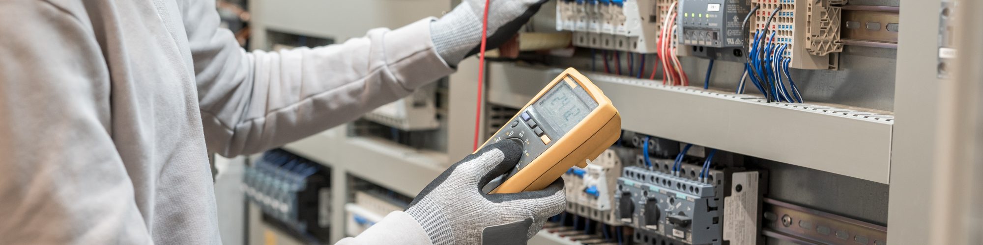 Electricians hands testing current electric in control panel